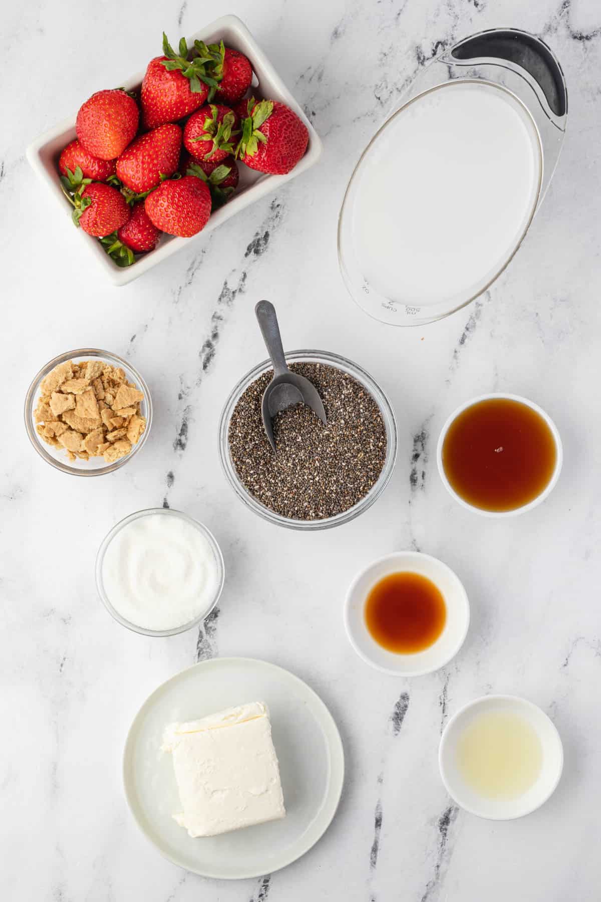 Ingredients for making strawberry cheesecake chia pudding in individual bowls.