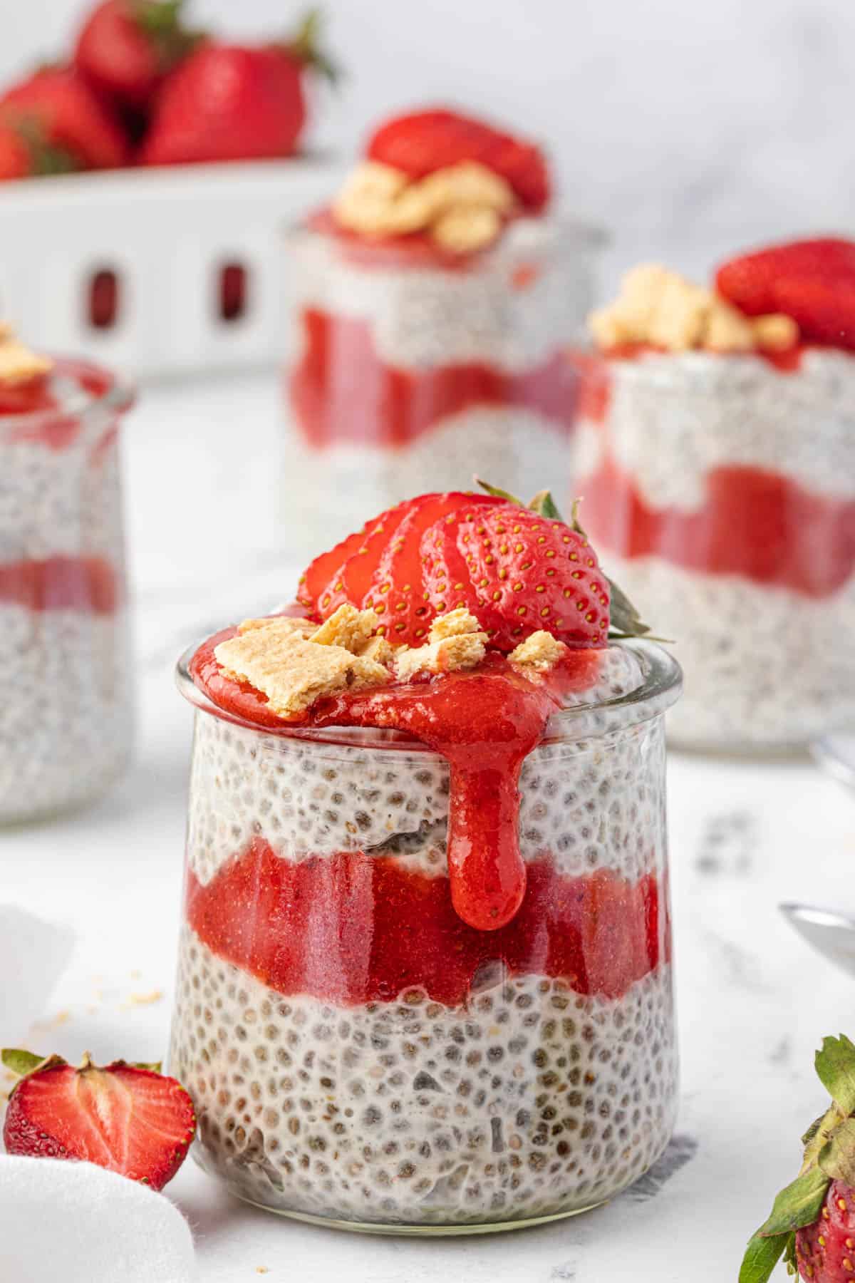 Strawberry sauce dripping down the side of a jar of coconut chia pudding with strawberry sauce.