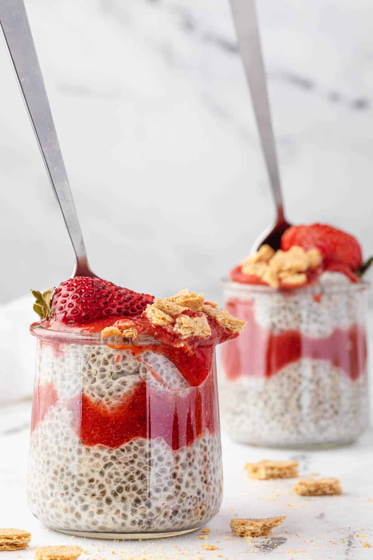 Two jars of coconut chia pudding with strawberry sauce.