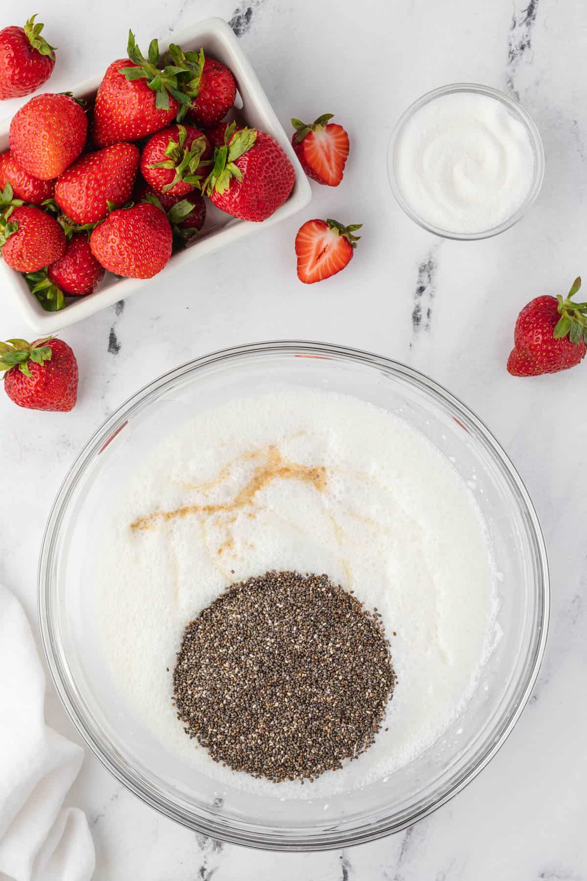 Adding vanilla and chia seeds to a bowl of coconut milk and cream cheese.