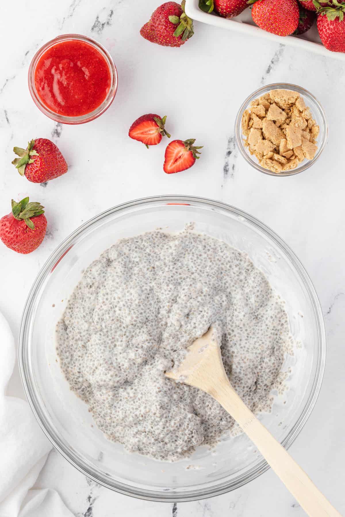 Thickened coconut cheesecake chia pudding once the liquid has been absorbed in a large bowl with a spoon.