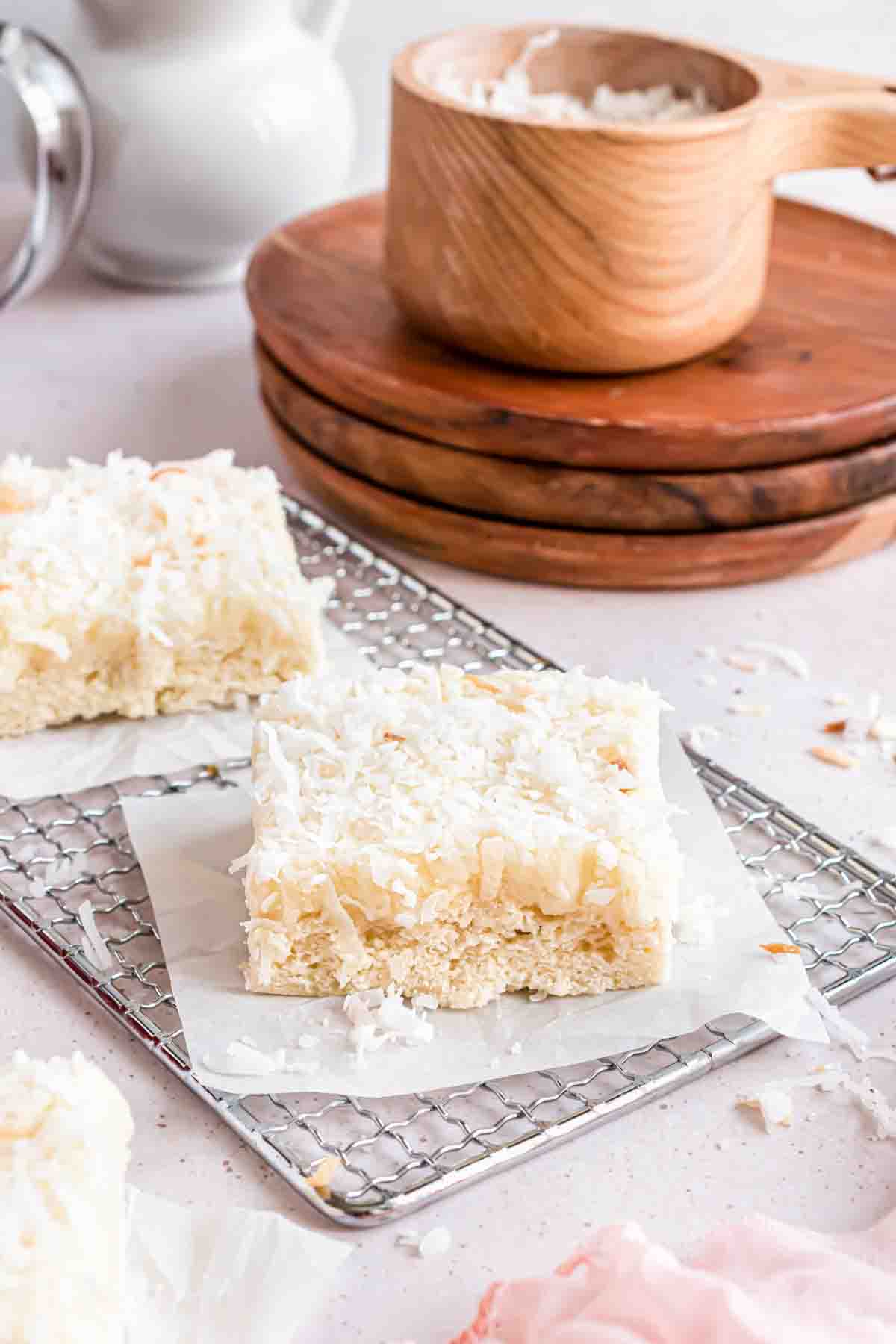 Frosted coconut sugar cookie bars on parchment paper squares.