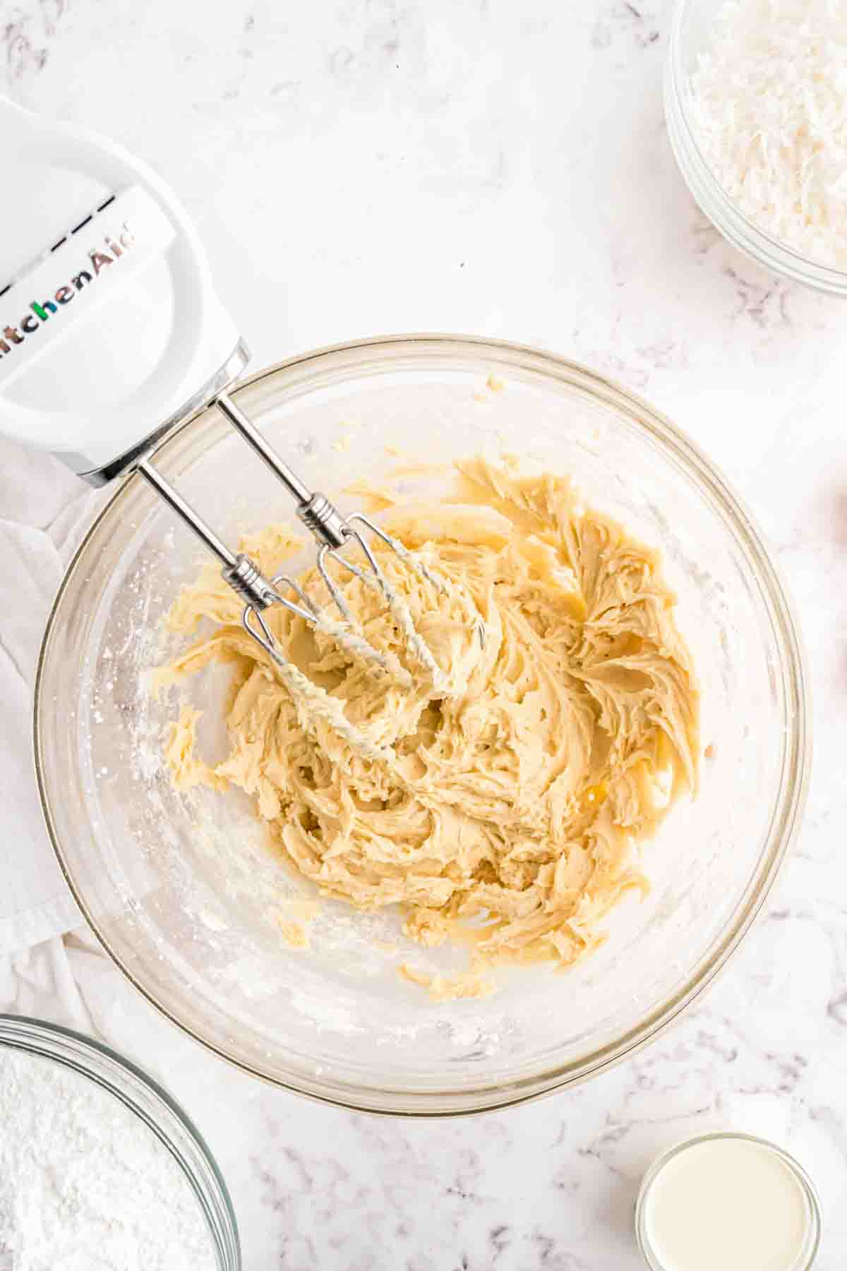 Beating cookie dough in a mixing bowl with a hand mixer.