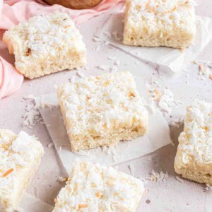 A frosted coconut sugar cookie bar on a square of parchment paper.