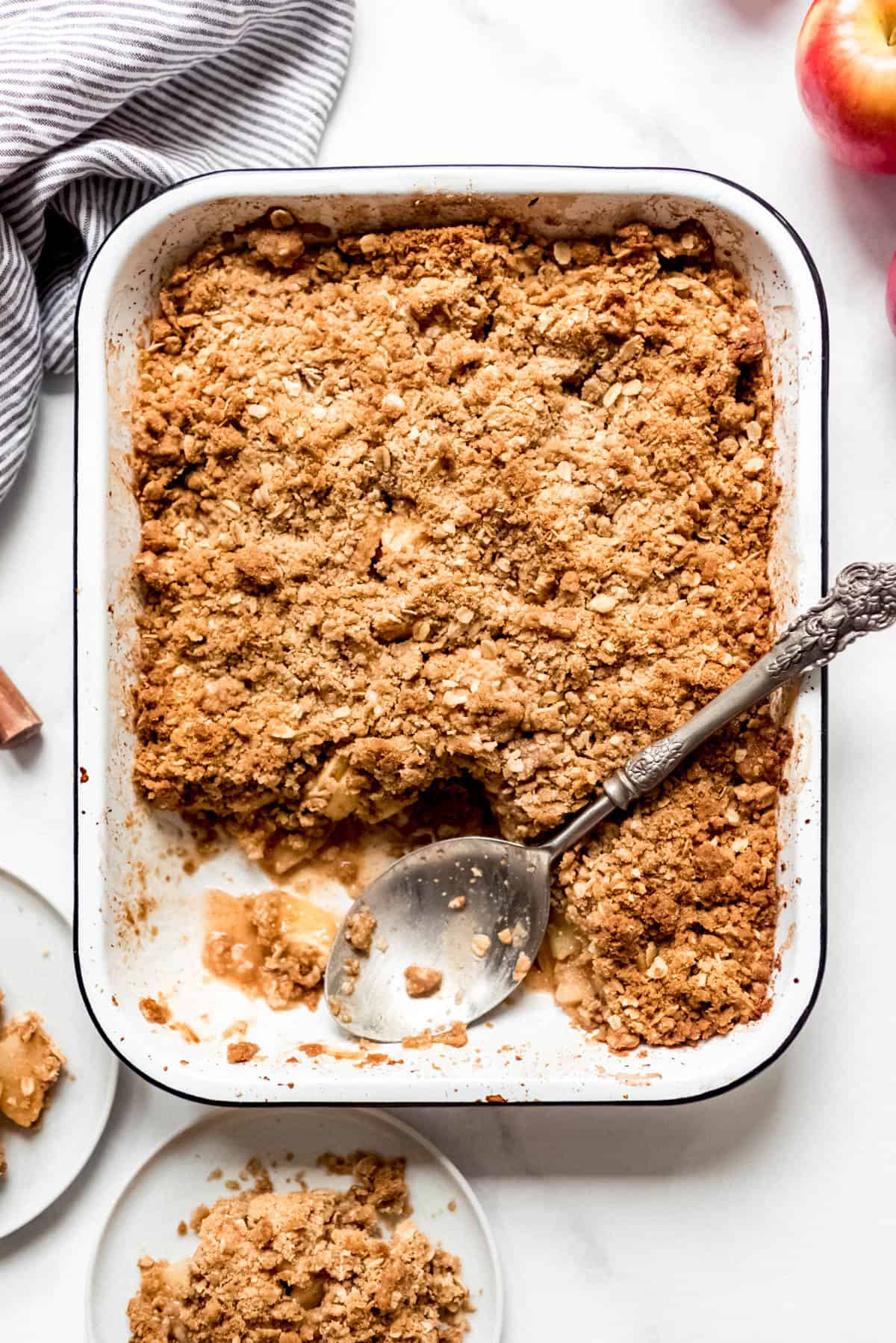 Apple Crisp in a 9x13-inch baking dish with a large serving spoon and a couple servings removed.