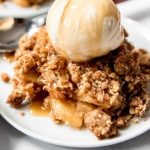 A large scoop of homemade apple crisp with oat topping and vanilla ice cream.