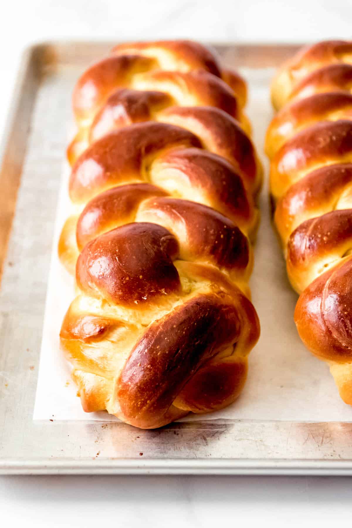 A loaf of braided challah bread on a baking sheet.