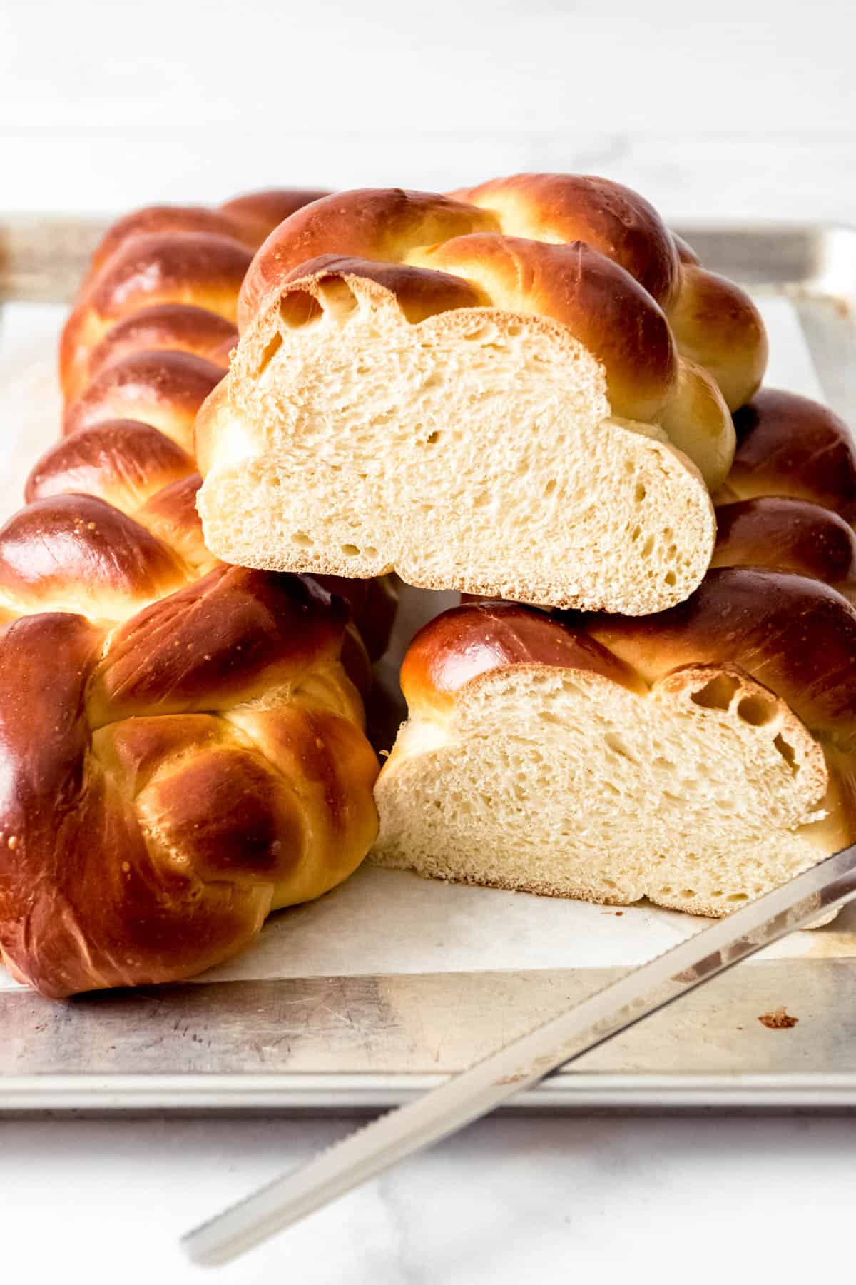 A loaf of challah bread sliced in half sitting on top of another loaf of challah bread.