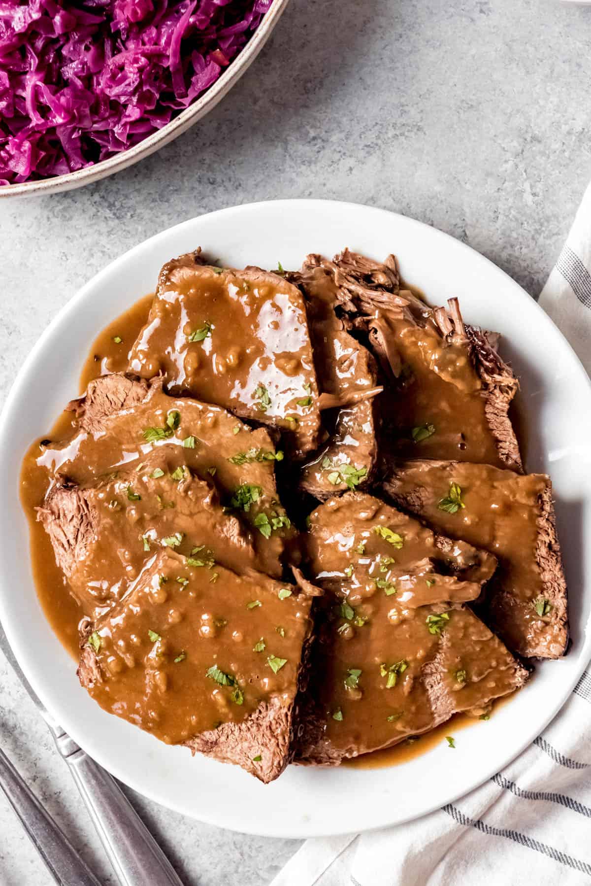 An image of German sauerbraten sliced on a plate with gravy on top.