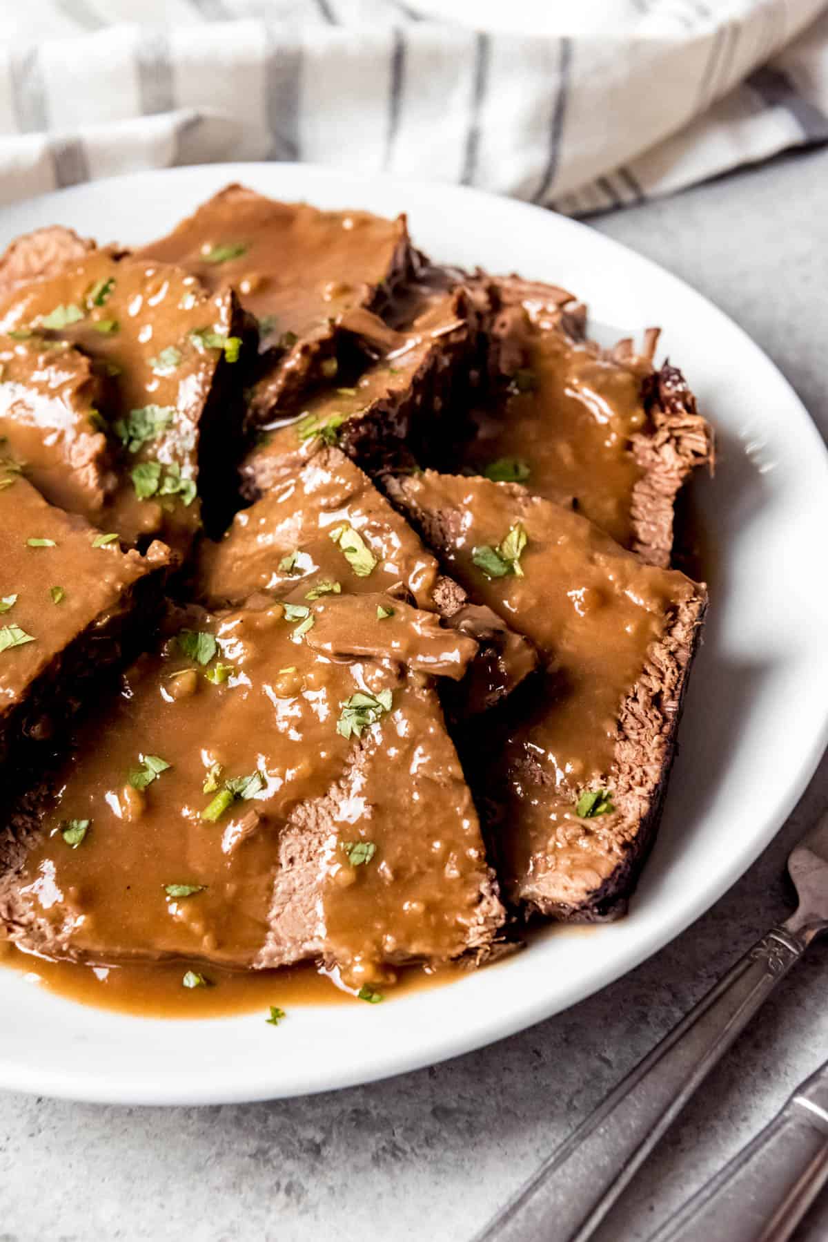 An image of sliced sauerbraten with gravy on a plate.