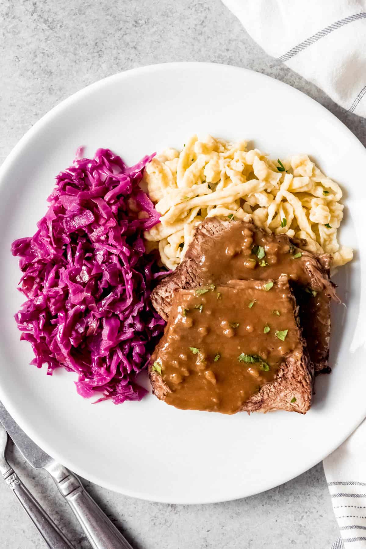 An image of authentic sauerbraten with rotkohl (German red cabbage) and spaetzle on a plate.