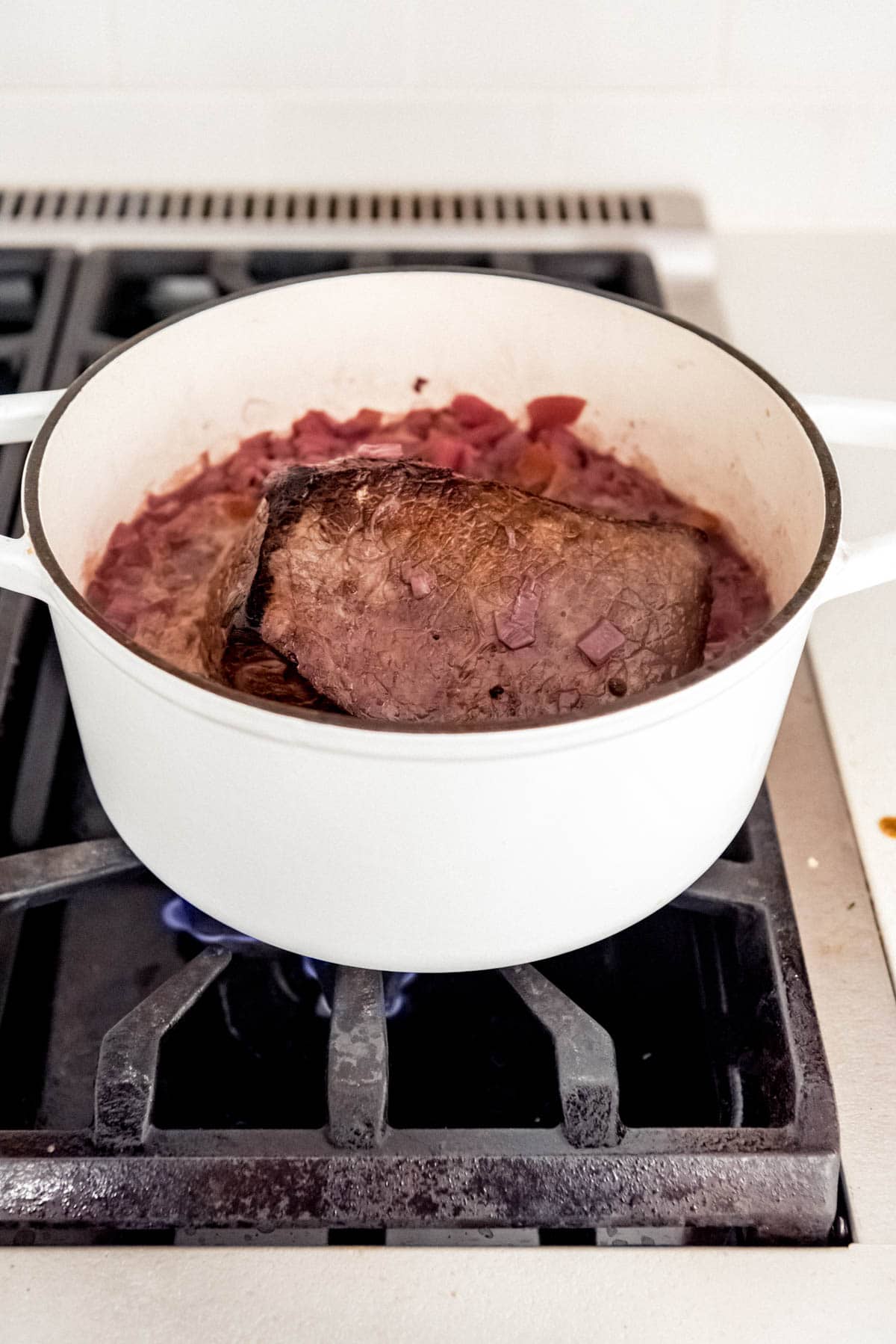 German Sauerbraten getting cooked with marinade in pot over stove.
