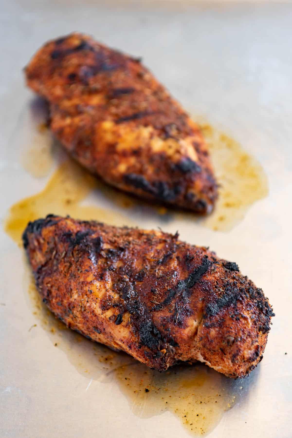 Two whole grilled Cajun chicken breasts