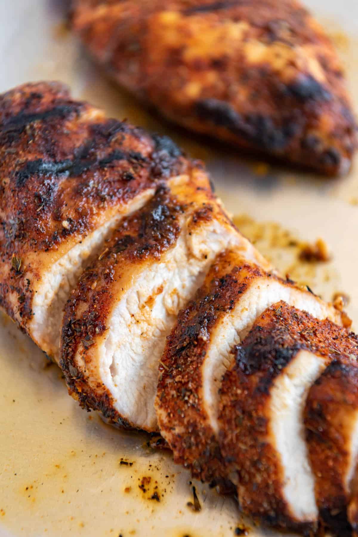 Grilled Cajun chicken breasts one is whole and one is sliced.