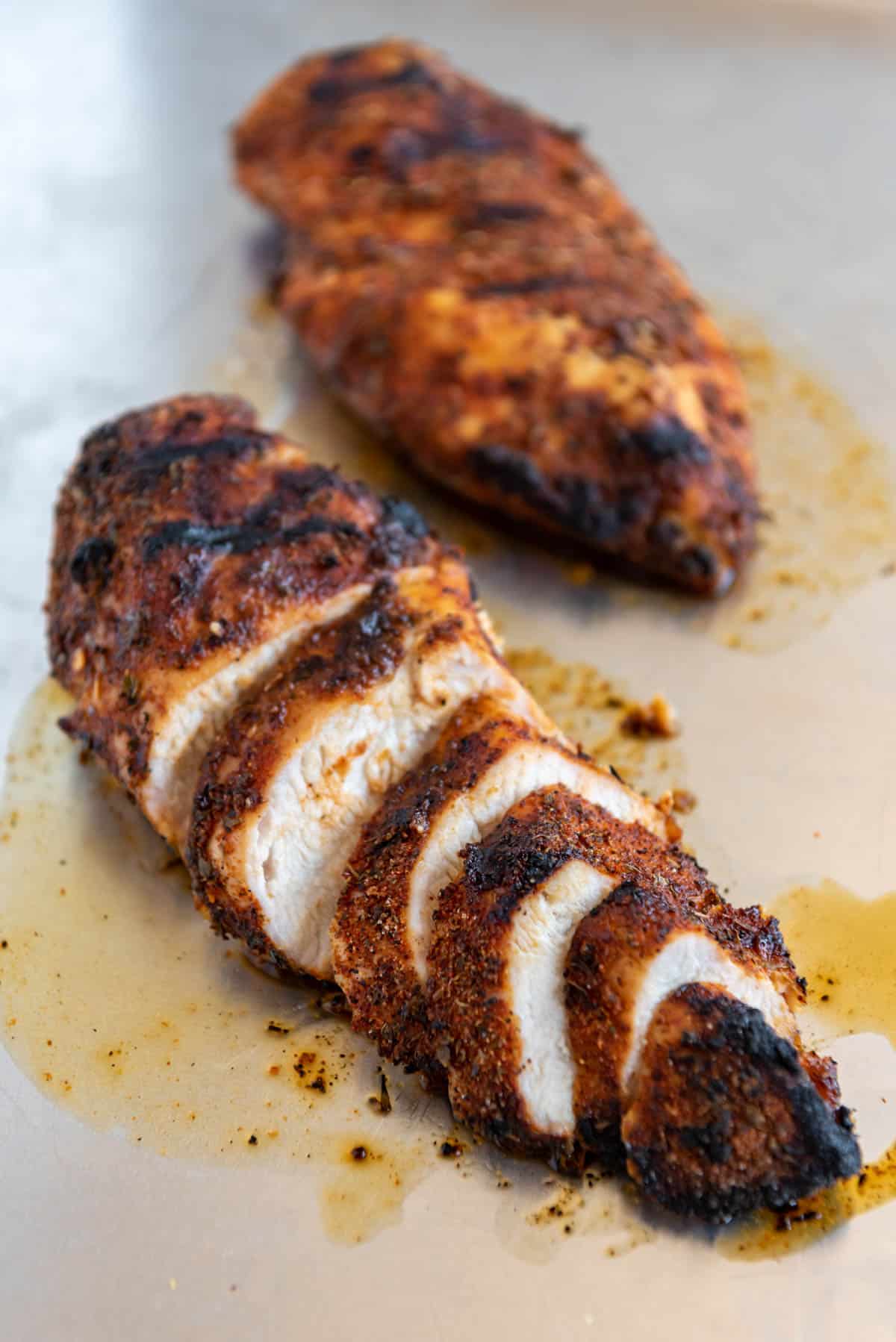 Seasoned and cooked grilled cajun chicken breasts sliced into coins to reveal juicy chicken inside.