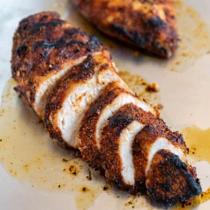 Seasoned and cooked grilled cajun chicken breasts sliced into coins to reveal juicy chicken inside.
