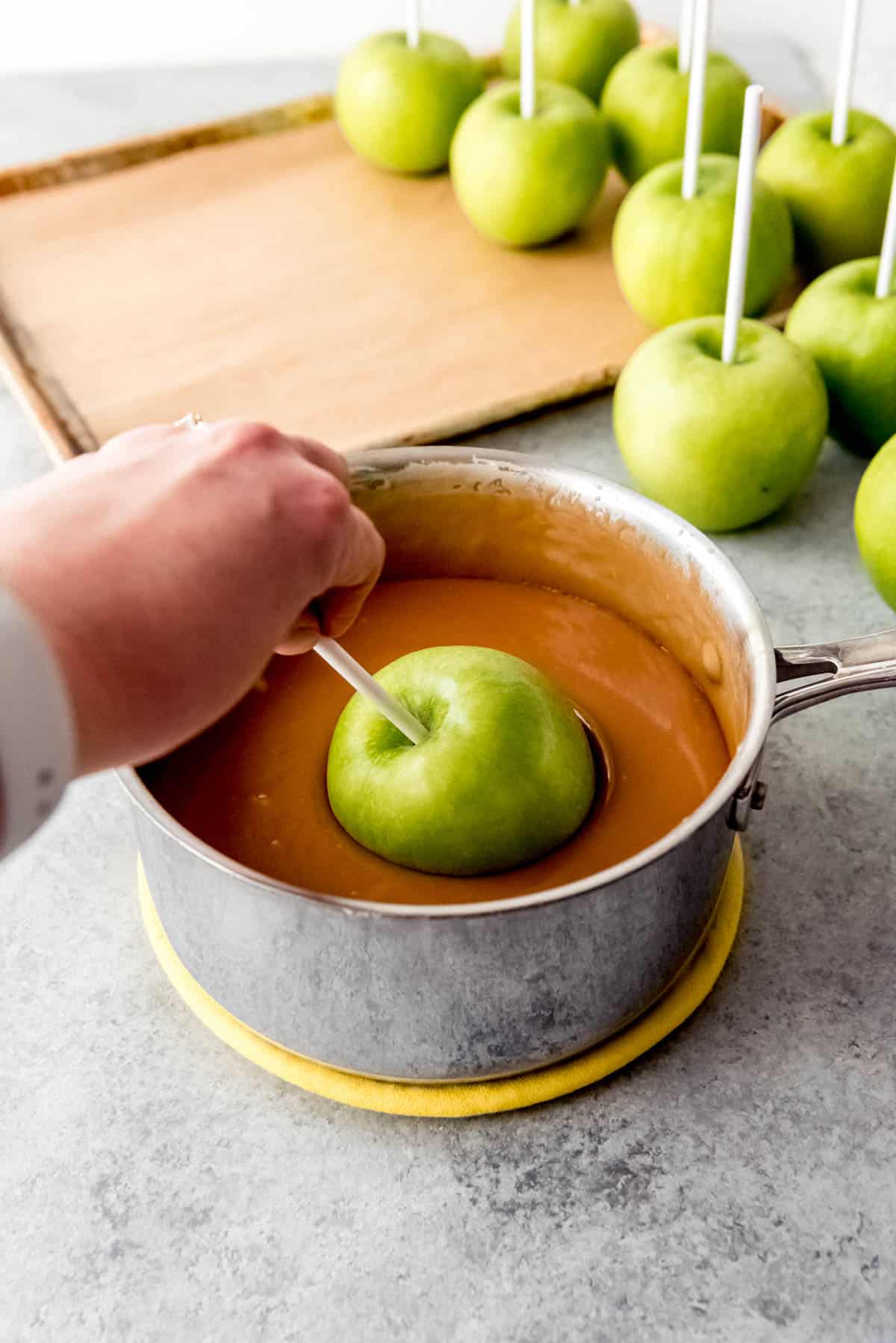 Dipping a green apple into homemade caramel.