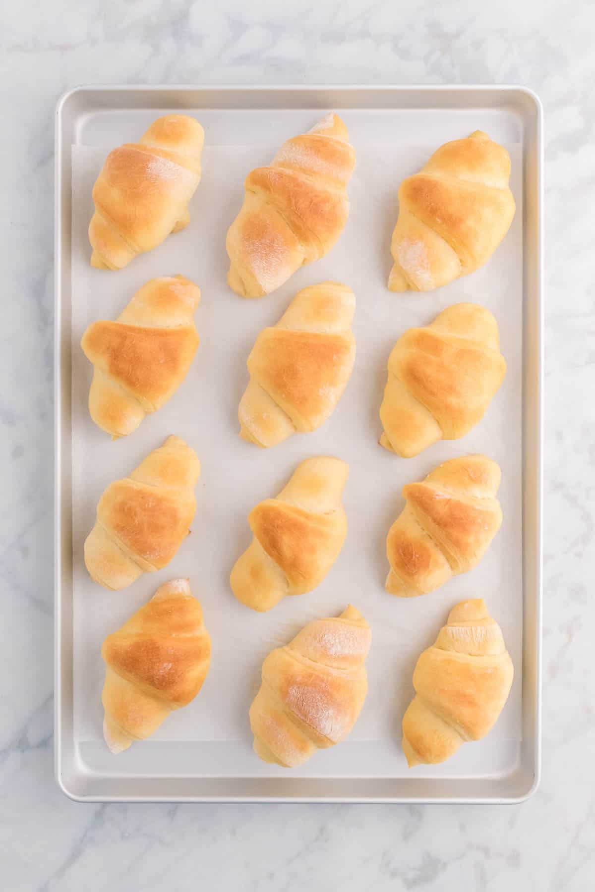 Top view of a baking tray with freshly baked crescent rolls. 
