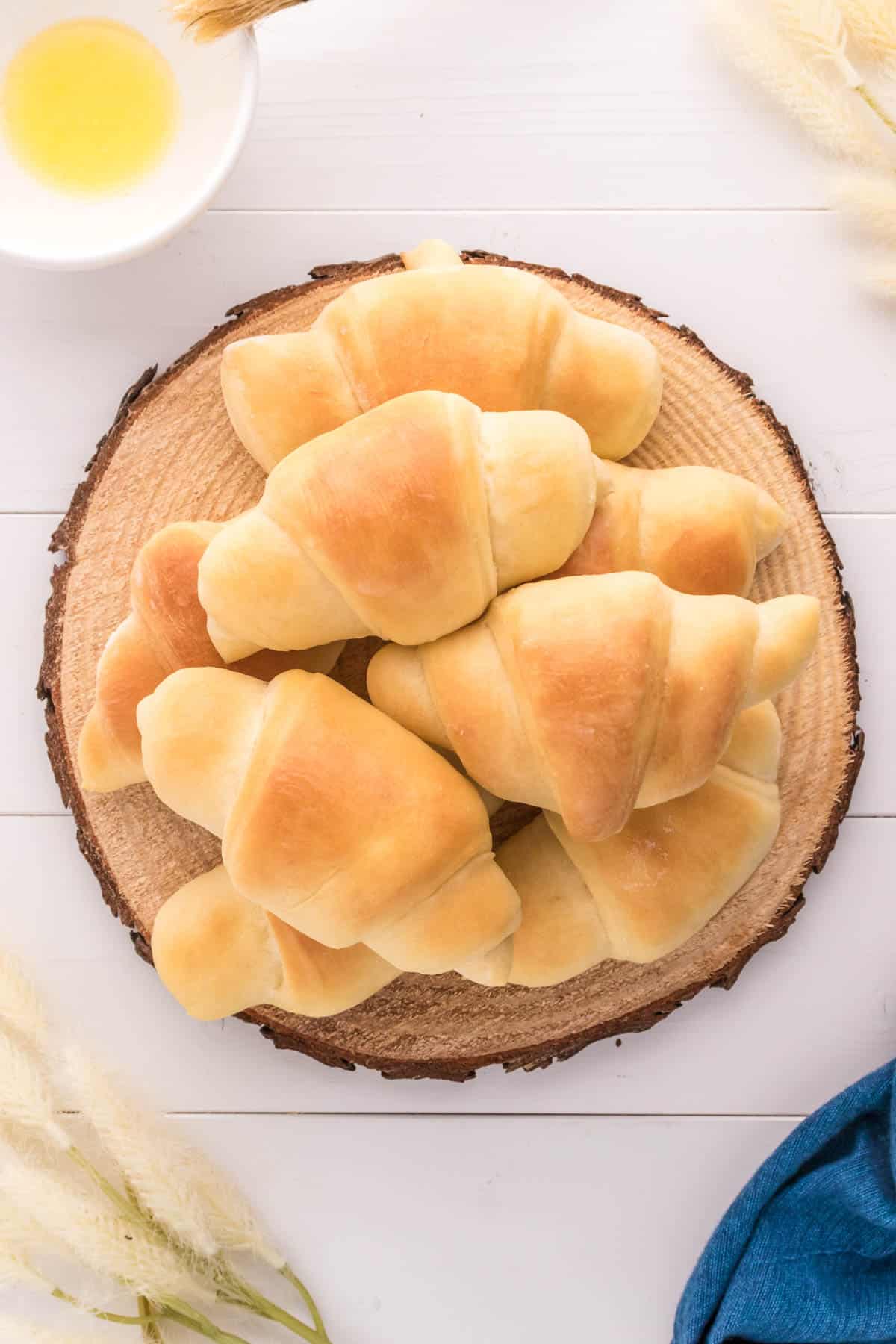 Top view of a pile of crescent rolls on a wooden circle. 