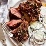 Lamp chops set on a plate next to creamy cucumber salad.