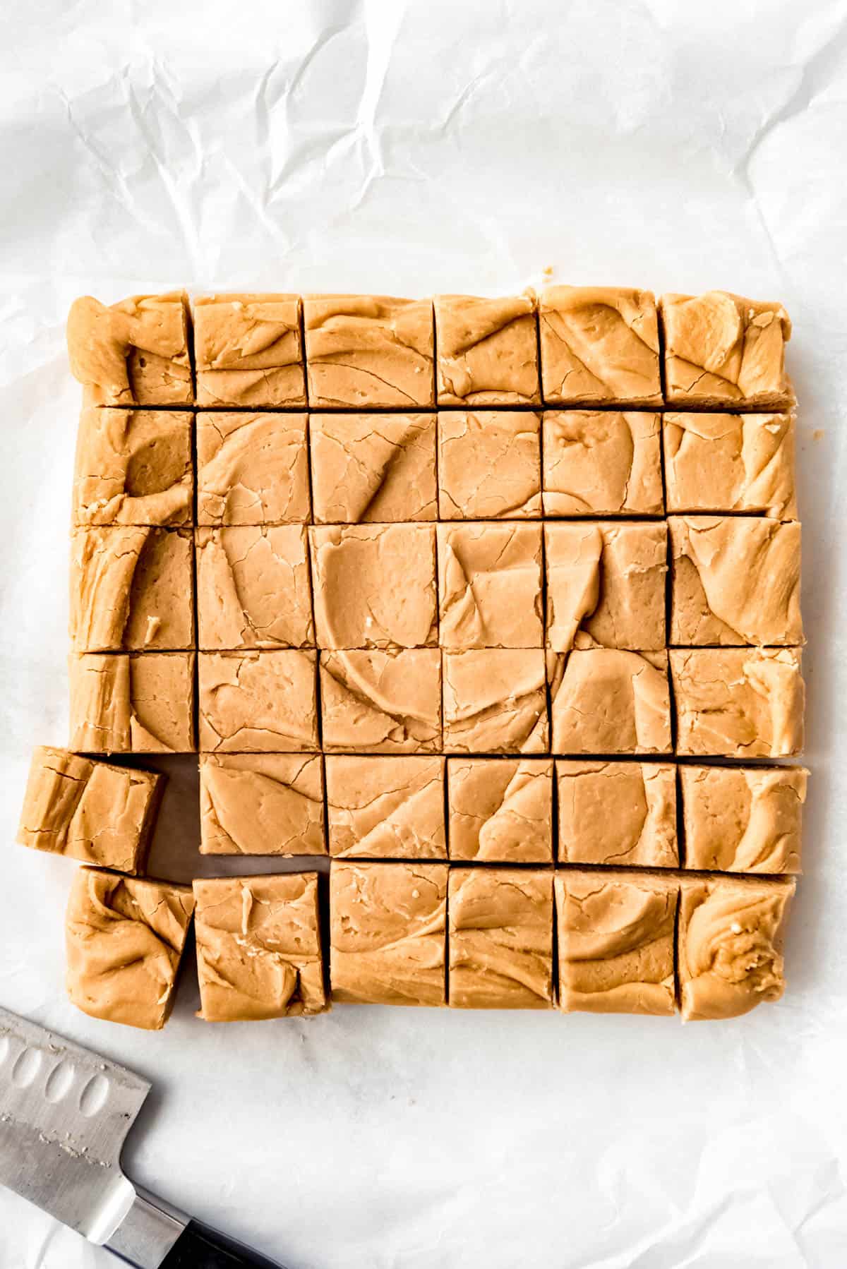 Top view of 36 squares of cut peanut butter fudge with a knife beside it. 
