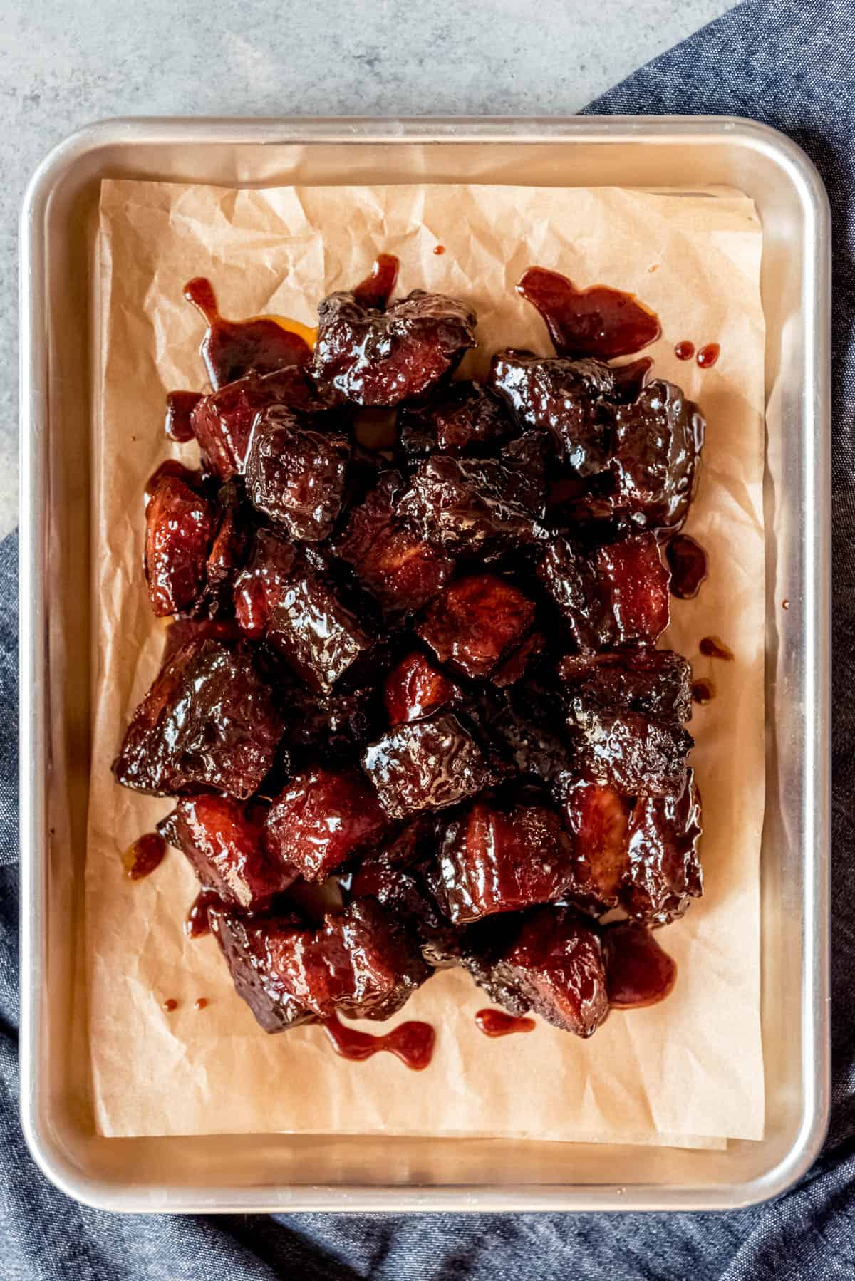 An image of cubes of pork belly that has been smoked on a Traeger grill and covered in barbecue sauce.