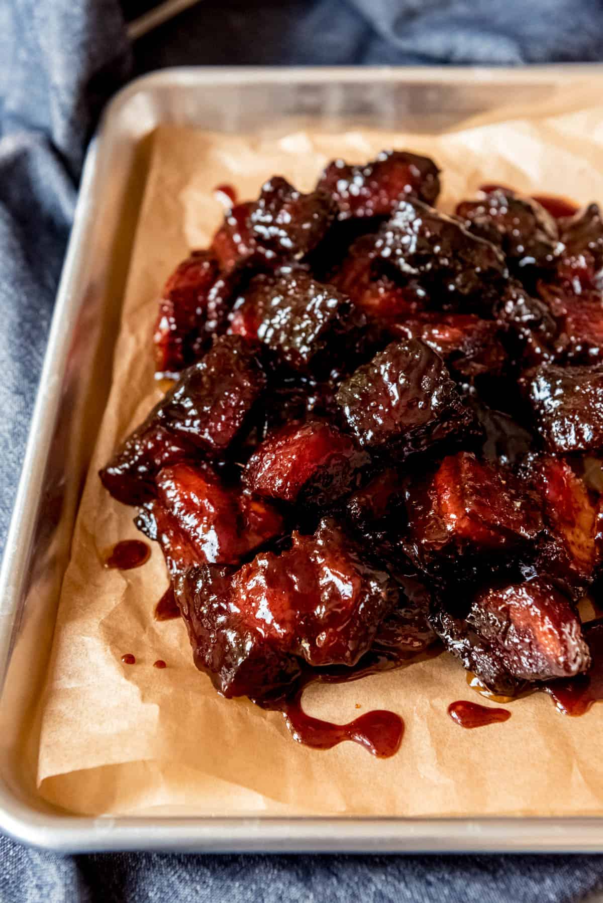 An image of smoked pork belly burnt ends on a baking sheet.