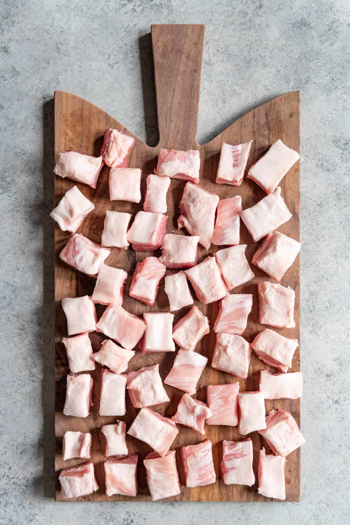 An image of cubes of pork belly on a cutting board.