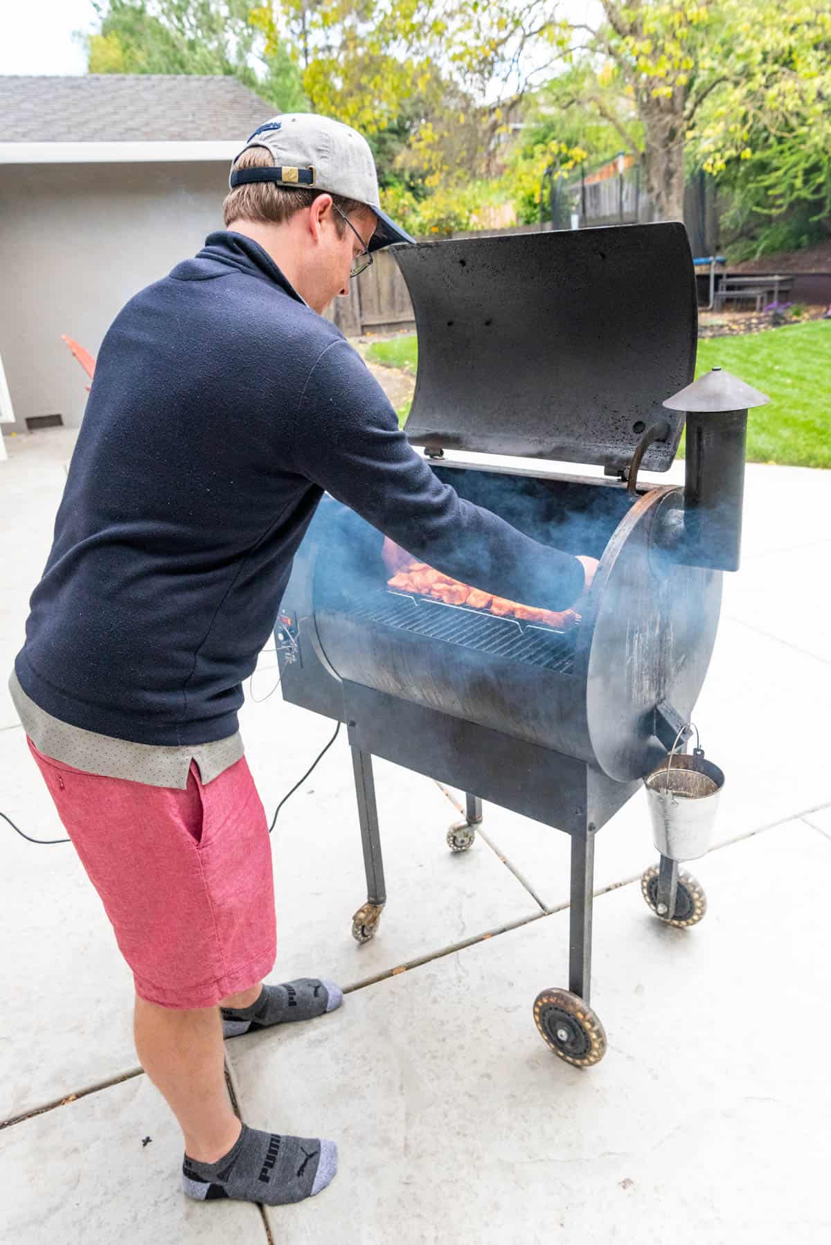 An image of a man putting pork belly on a smoker to make burnt ends.