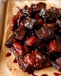 An image of smoked pork belly burnt ends on a baking sheet.