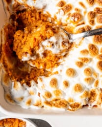 A scoop of Sweet Potato Casserole with marshmallow and pecan topping.