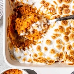 A scoop of Sweet Potato Casserole with marshmallow and pecan topping.