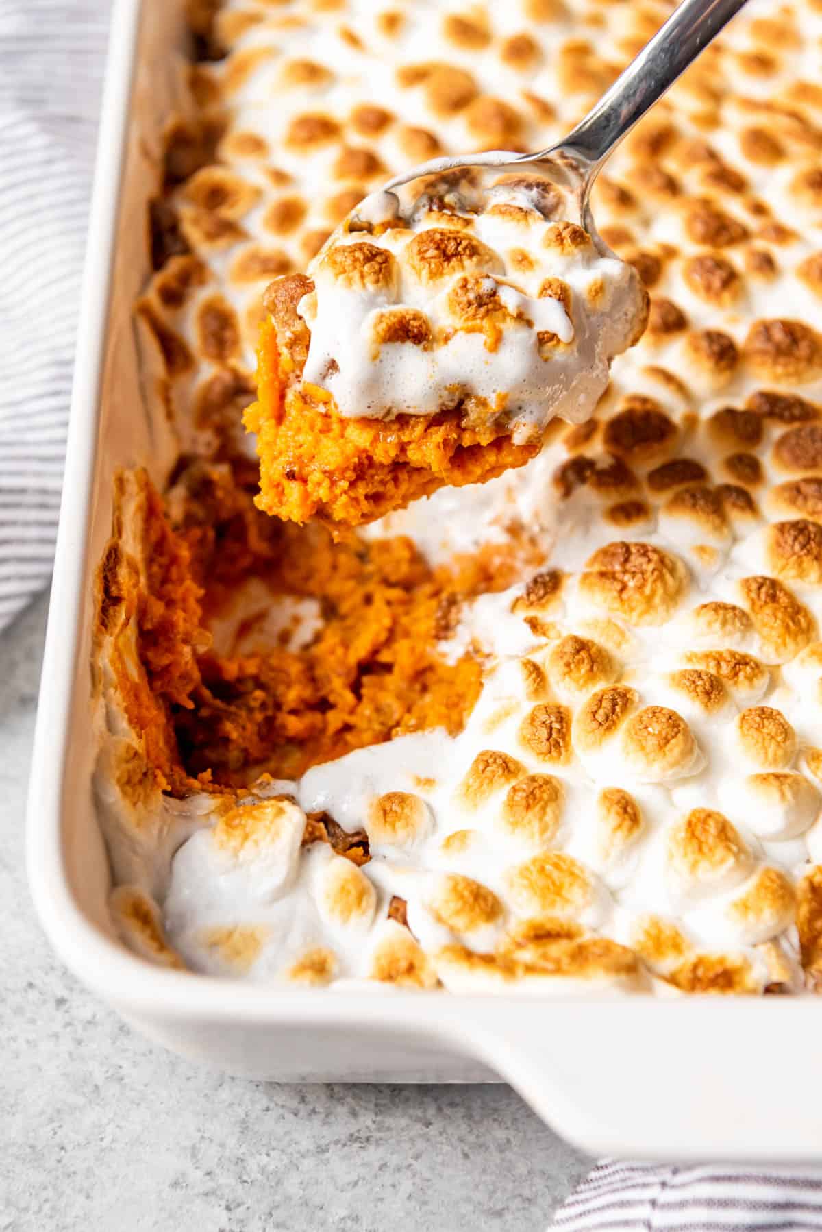 An image of a spoonful of sweet potato casserole being lifted out of the baking dish.