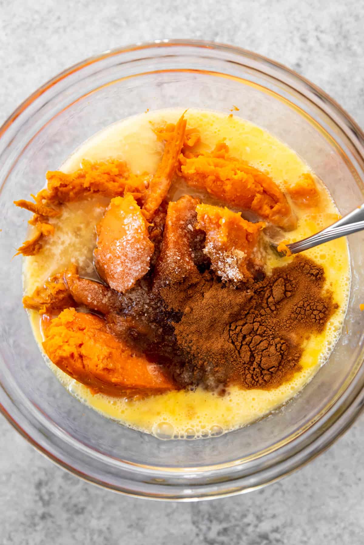 An image of the ingredients for sweet potato casserole in a bowl for mashing.