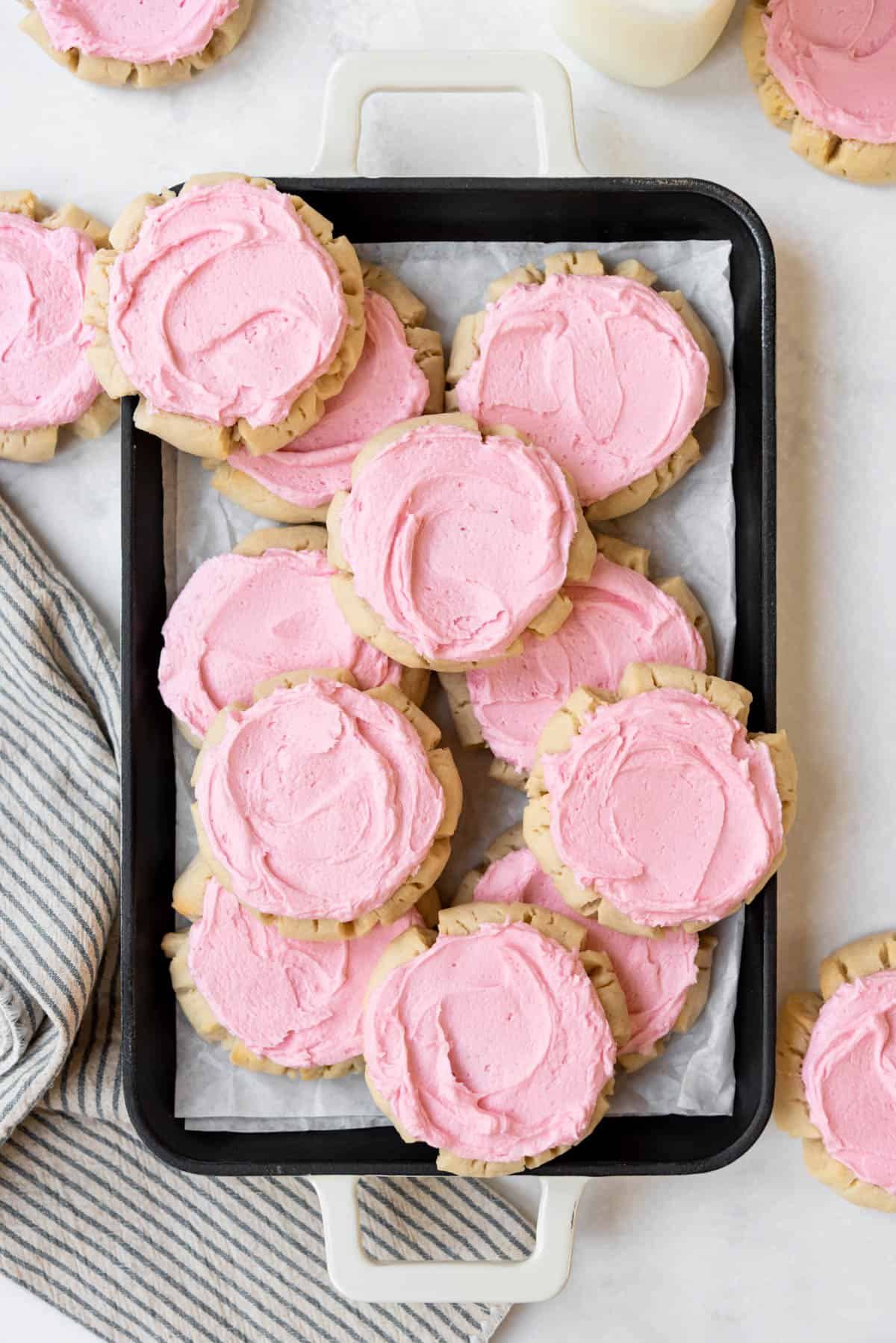 An overhead image of pink frosted sugar cookies arranged on a serving tray.