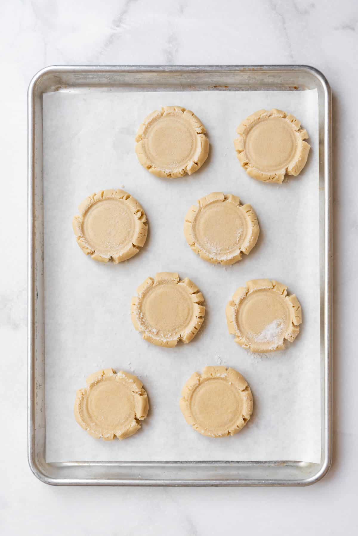 Unbaked sugar cookie dough on a baking sheet lined with parchment paper.