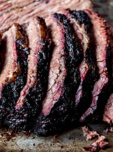 An image of slices of Texas-style smoked beef brisket with a dark bark and pink smoke ring.