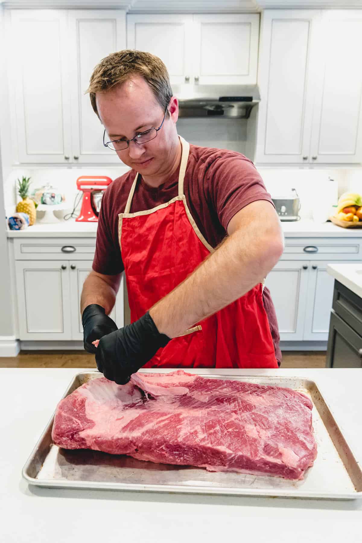 An image of a man trimming a beef brisket.