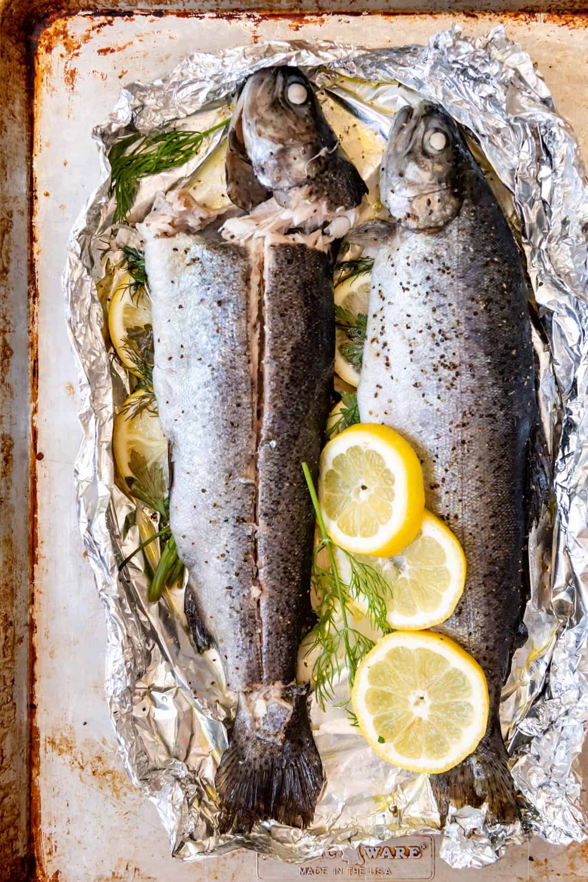 An image of whole baked rainbow trout sliced down the side to remove fillets of fish without the bones.