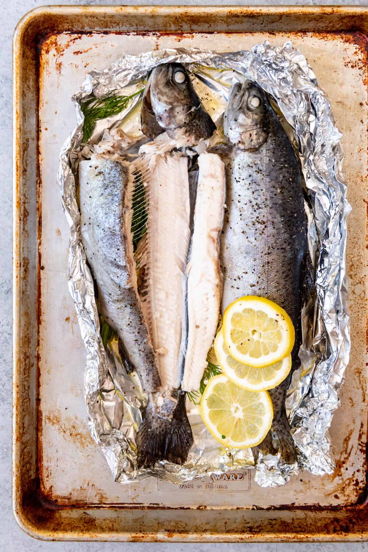 An image of baked rainbow trout on a baking sheet.