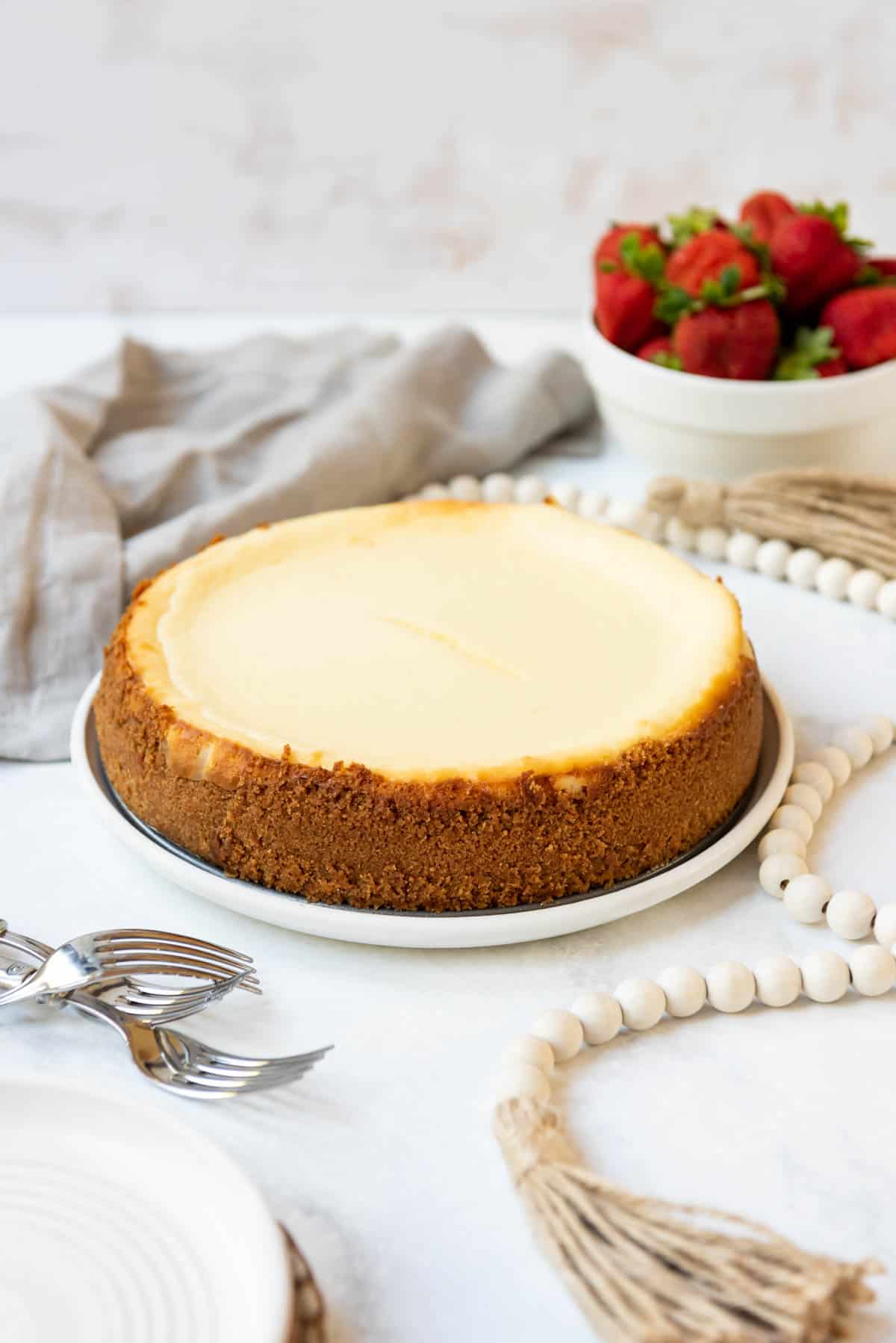 Plain cheesecake on a plate next to a bowl of berries. 