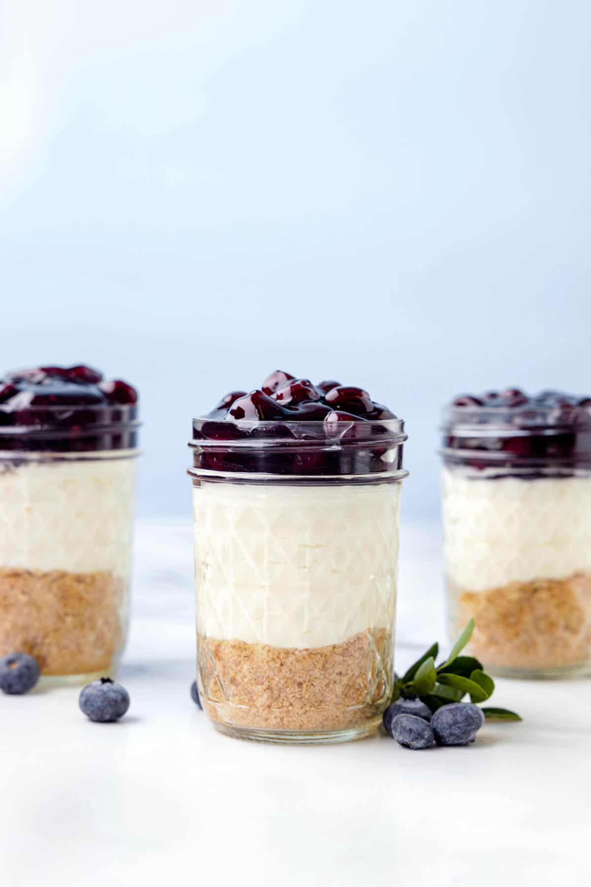 Homemade cheesecake jars topped with blueberry pie filling.