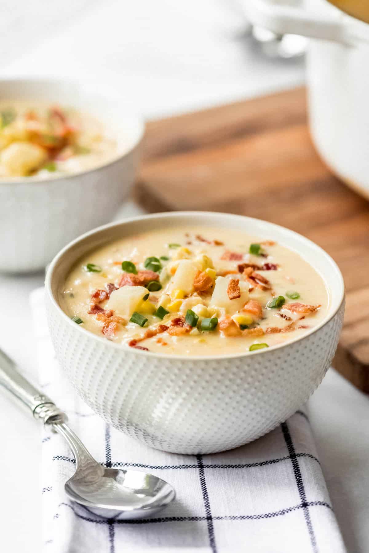 A bowl of corn chowder with potatoes and bacon.