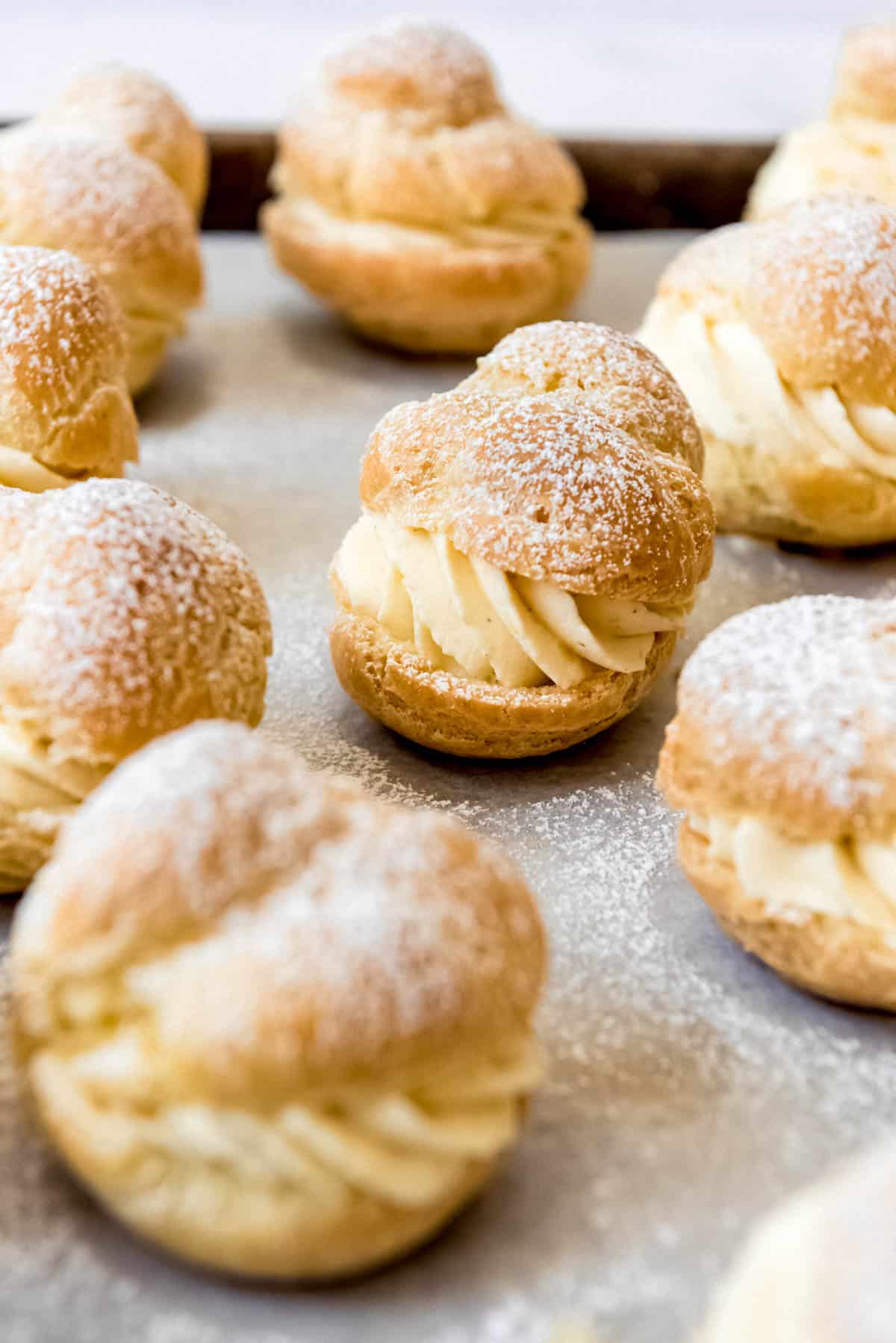 Cream puffs filled with custard filling on a baking sheet.