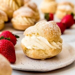 An image of a cream puff on a plate with whole strawberries.