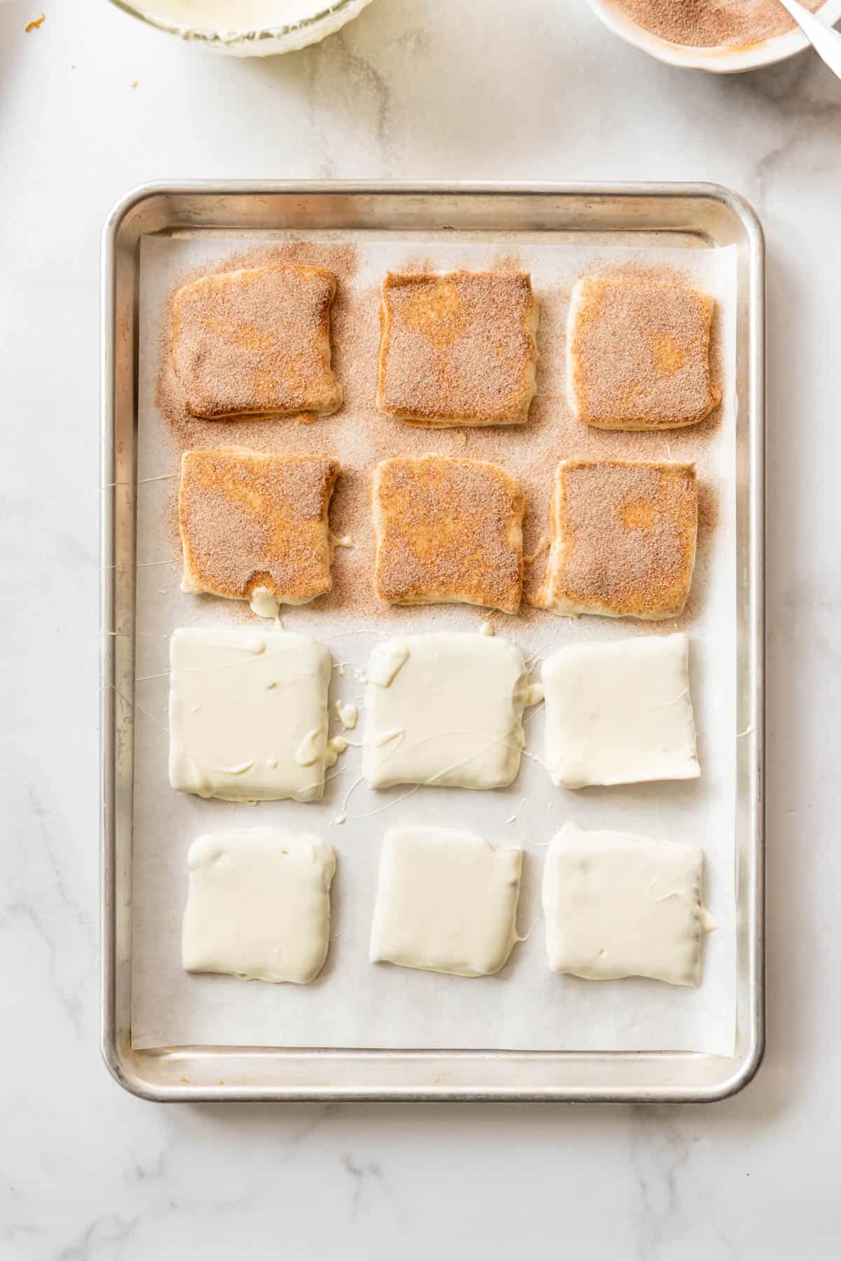 An image of Toffee squares dipped in white chocolate and then getting sprinkled with a cinnamon sugar mixture.