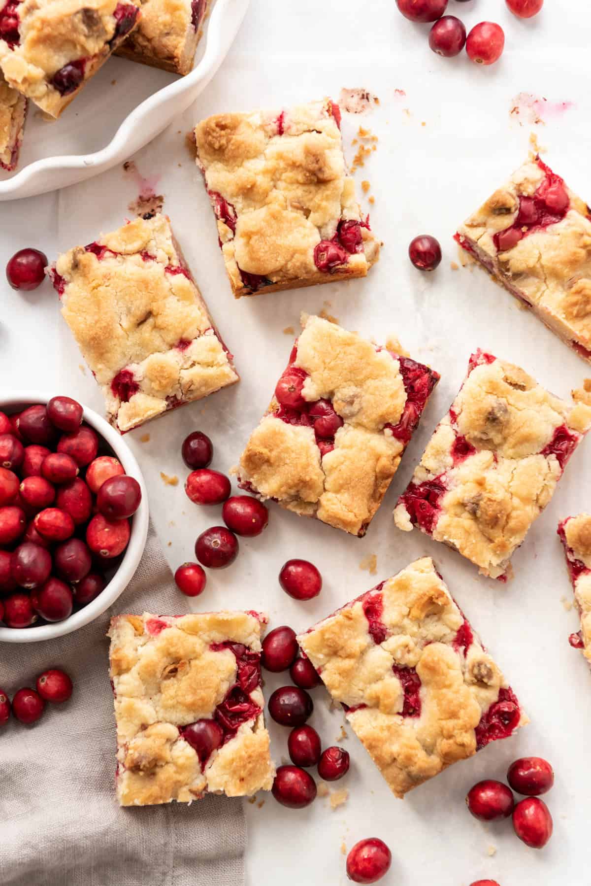 An overhead image of cranberry shortbread bars with fresh cranberries scattered around them.