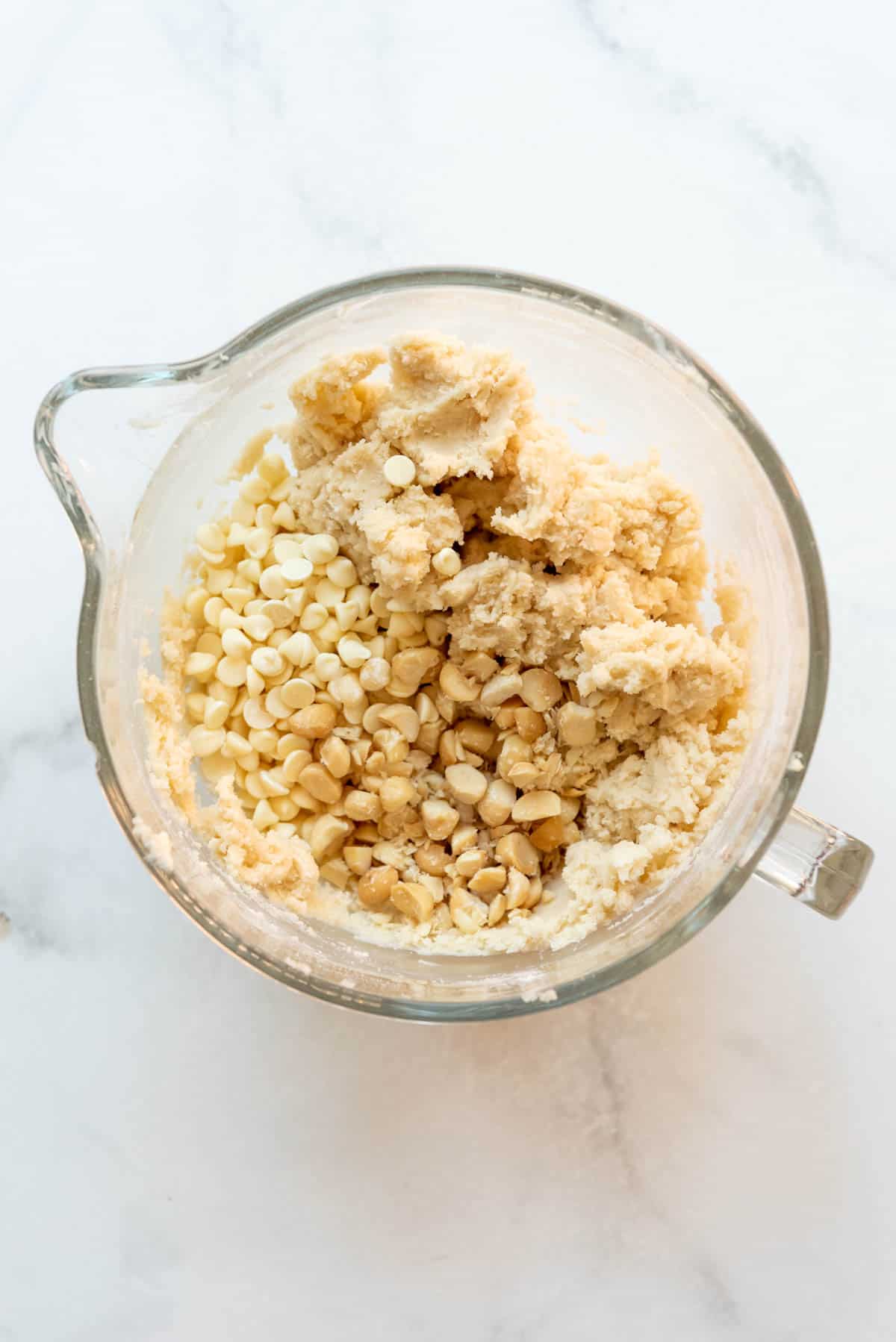 Adding macadamia nuts and white chocolate chips to shortbread dough.