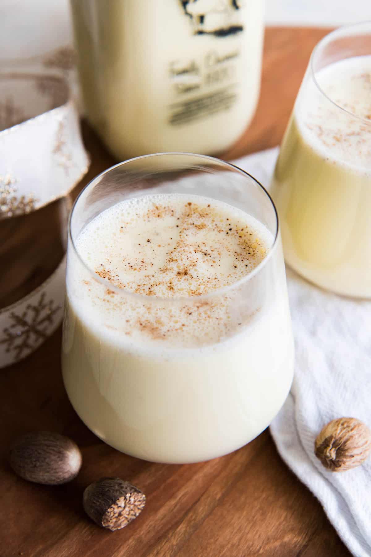Close up of two glasses of eggnog topped with grated nutmeg.
