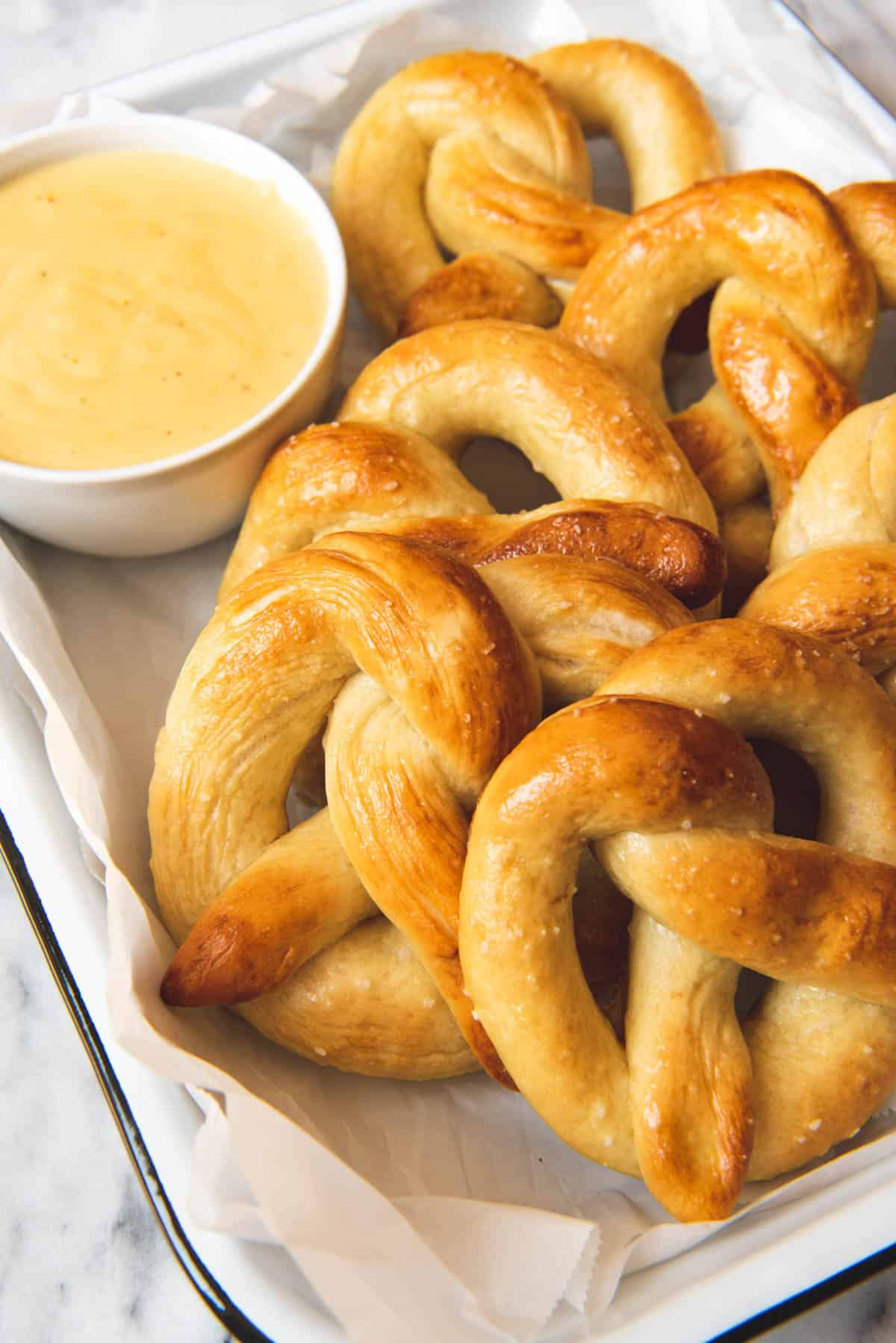 An image of pretzels on a plate with cheesy mustard sauce in a little dish to dip pretzels in.